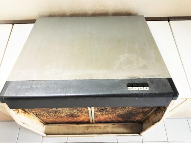 油汚れでベタベタになったレンジフードの写真(現場撮影風、ファンに油がこびりついた状態)